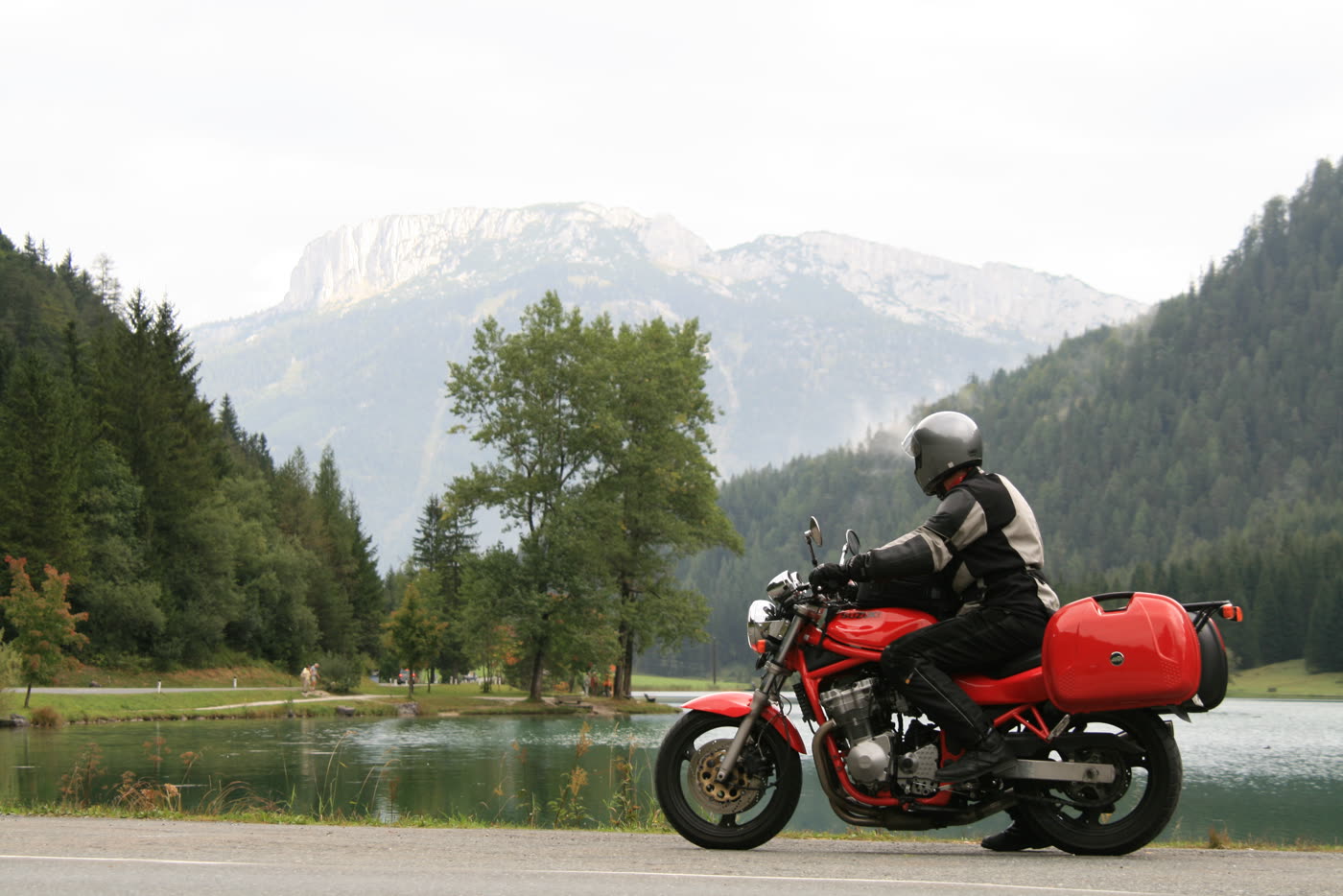 Motorrad am Ufer des Pillersees vor bewaldeten Bergen